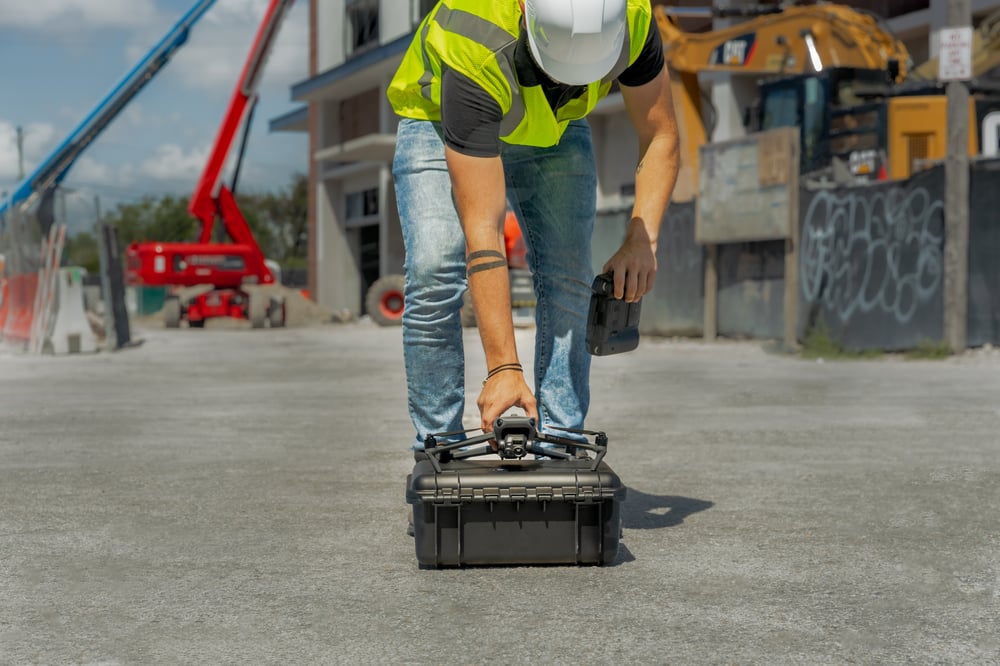 Man picking up a drone at a construction site